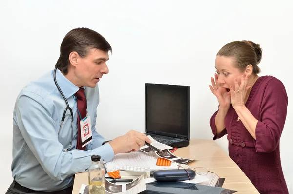 Male doctor indicates ultrasonic snapshot surprised woman patient at his desk — Stock Photo, Image