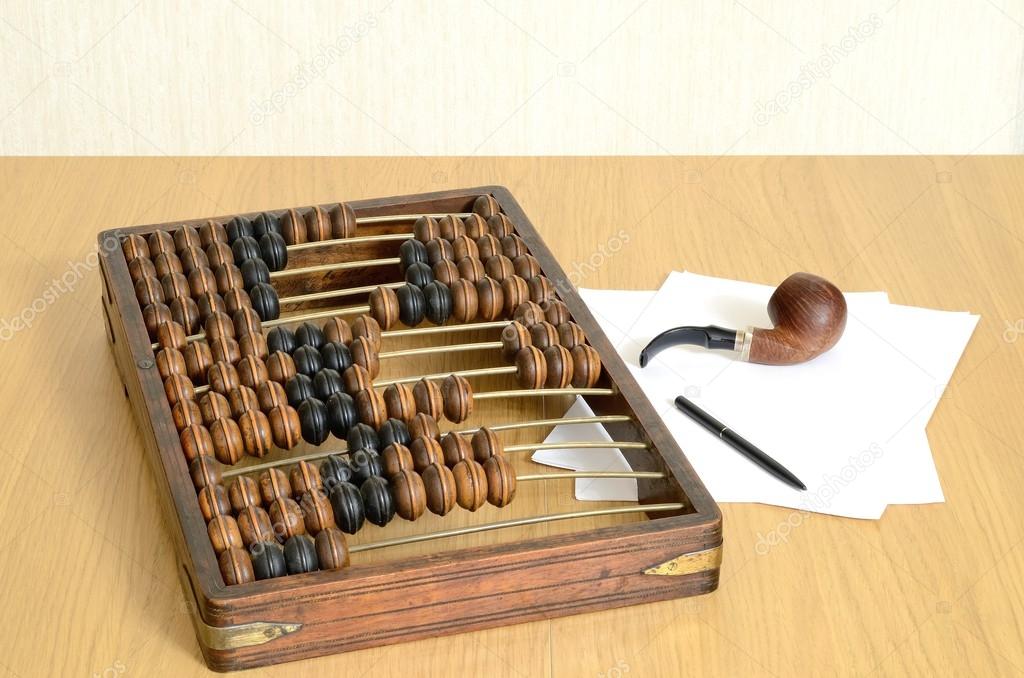 Abacus arithmetical old for accountants, sheets of paper, a pen and a pipe for of tobacco smoking in still life