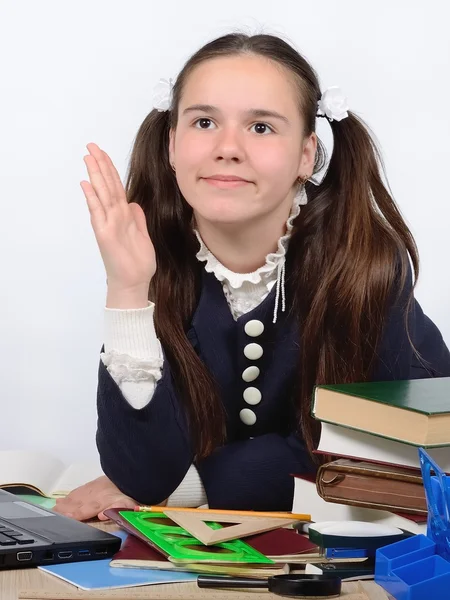 Teen schoolgirl at a school desk raises her hand to respond a lesson — Stock Photo, Image
