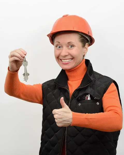 Mujer trabajadora de la construcción sonríe y se regocija en su mano mostrando las llaves de la nueva casa —  Fotos de Stock