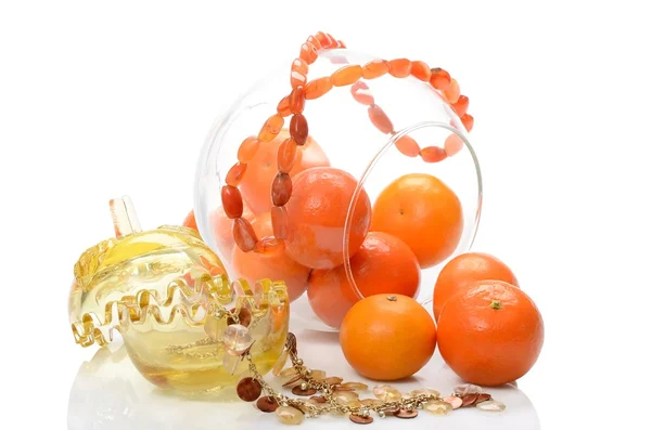 Ripe fruit tangerines in glass vase transparent and from amber necklace still life on white background — Stock Photo, Image