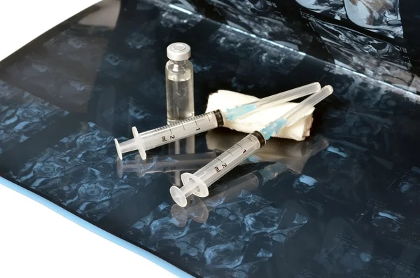 Twee spuiten waren en fles met een een injectie medicijnen liggen op de radiografie op een witte achtergrond Rechtenvrije Stockafbeeldingen