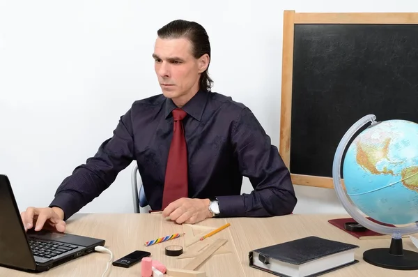コンピューター作業中のテーブルで厳格な教師深刻な男性 — ストック写真