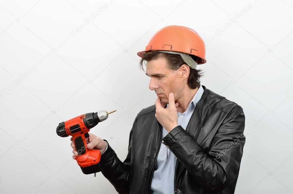 A man working in perplexity pondered look at a tool screw gun