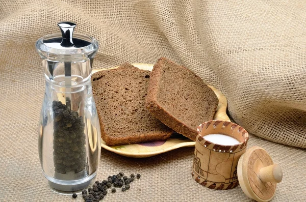 Kuchnia martwa na tle płótnie: sól solniczka, chleb żytni, pieprzu do pieprzu, dzbanki — Zdjęcie stockowe
