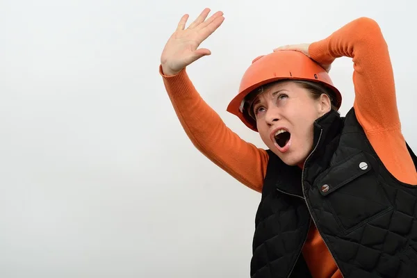 De bouw van de vrouw in een helm is bang gevaar een bedreigende vanaf de top en verdedigd gestrekte arm — Stockfoto