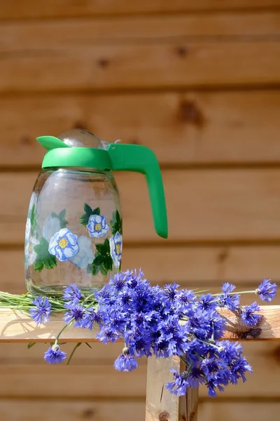 Bouquet de fleurs sauvages bleues bleuets et cruche d'eau - année nature morte sur un fond en bois — Photo