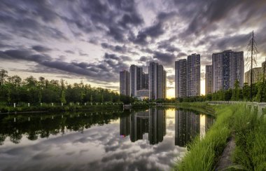 Gold Mark Şehir Parkı 'nda gün batımında gölde yansıması olan binalar. Alacakaranlık döneminde Hanoi şehir manzarası