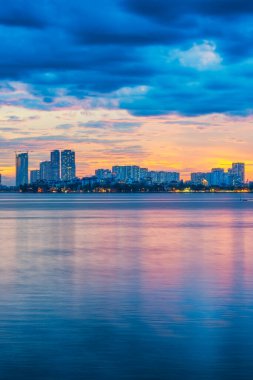 Hanoi, Vietnam 'daki Batı Gölü' nün üzerinde güzel bir gün batımı. Renkli bulutlar, şehir silueti ve sudaki huzur yansımaları.