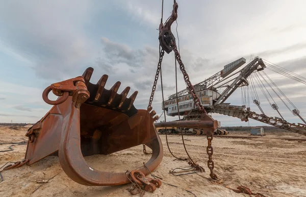 En jätte rostig hink i bakgrunden stenbrottet grävmaskinen utrustning för utvinning av sand från stenbrottet. — Stockfoto