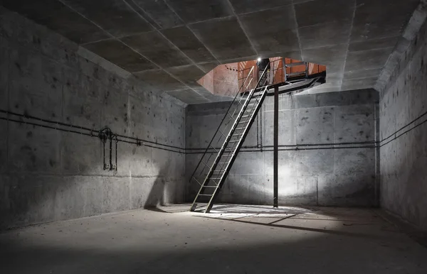 Sala de hormigón bajo tierra con una escalera a la superficie de la que proviene la luz. Eje de ventilación técnica de la sala subterránea — Foto de Stock