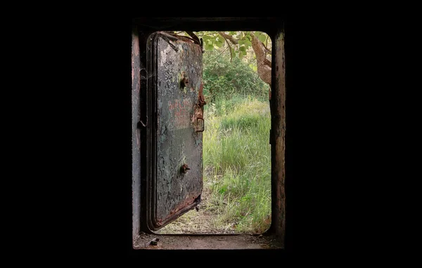 Öffnen Sie die Tür des alten Bunkers. der Blick aus der dunklen Natur hinter einer Tür. — Stockfoto