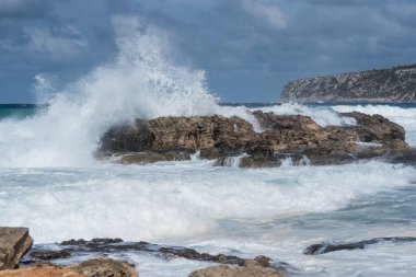 Deniz Burnu. Dalgaların kıyıdaki kayalara şiddetle çarpmasıyla dalgalı bir deniz günü. Formentera Adası, İspanya.