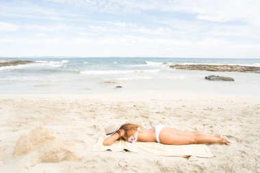 Kumsalda güneşlenen güzel bir kadın. Düşük ihtimal. Formentera Adası, İspanya.