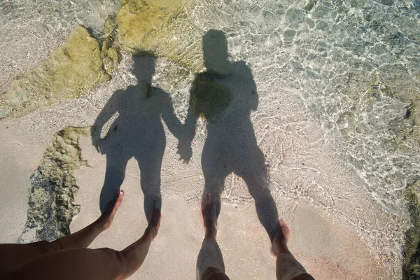 The shadow of a man and a woman in love reflected on the seashore.