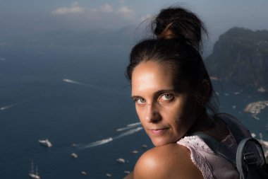 Güneşli bir yaz gününde güzel bir deniz manzarasıyla kameraya bakan güzel bir kadın. Capri Adası.