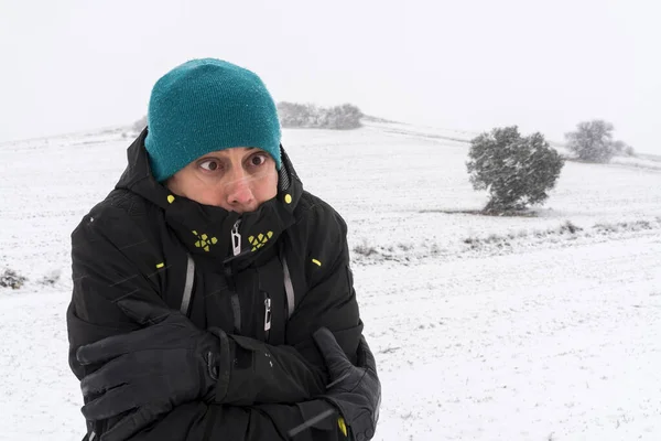 Very cold man with coat, hat and gloves, in the middle of a snowfall. Spain.