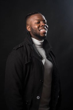 Yakışıklı siyahi adam gülümsüyor. Orta atış. Siyah arkaplan