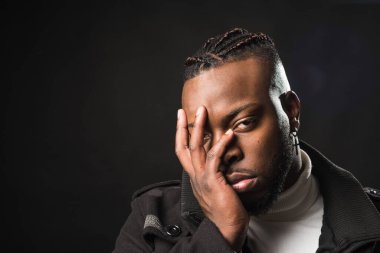 Sıkıcı ve yarı uykulu zenci bir adamın eli suratında..