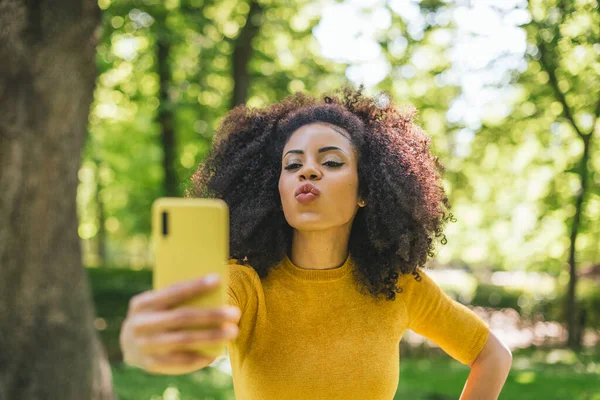 Mulher afro bonita tirando uma selfie soprando um beijo. — Fotografia de Stock