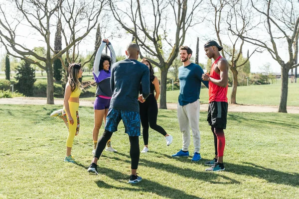 Grupo de corredores amistosos hablando en un parque antes de entrenar. —  Fotos de Stock