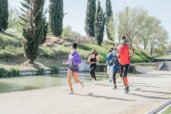 Group of runners with mask training in a park.