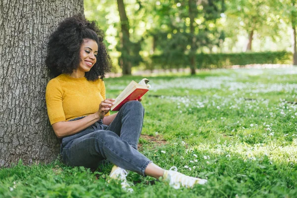 Hübsche Afro-Frau liest ein Buch im Garten. — Stockfoto