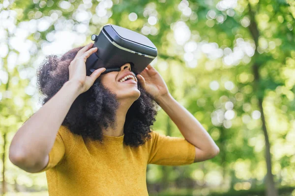 Afro mujer con gafas de realidad virtual en un jardín. —  Fotos de Stock
