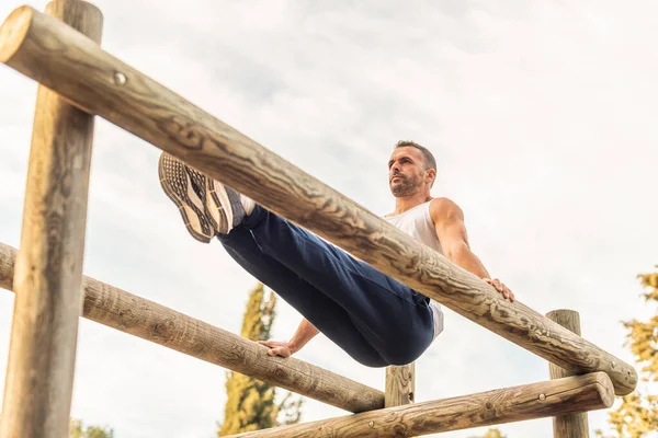 Male athlete exercising on a wooden structure — Foto de Stock