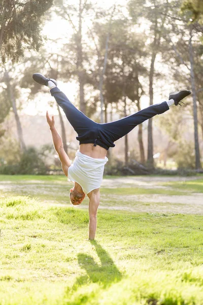 Front view of a gymnastic man handstand on one hand doing acrobatic posture —  Fotos de Stock