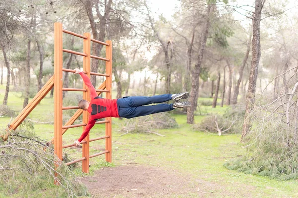 Rear view of a young man doing exercises on vertical bar in park — Foto de Stock