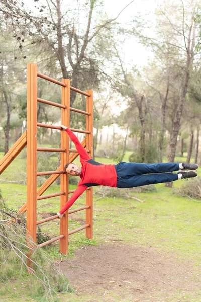 Young man doing exercises on vertical bar in park — Foto de Stock