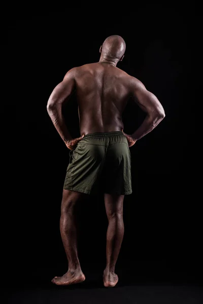 Вид ззаду м'язистого чоловіка, що стоїть з руками на талії — стокове фото