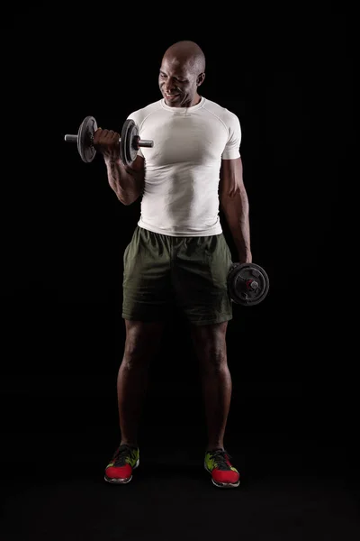 М'язистий чоловік з білою футболкою, що стоїть, робить вправи для біцепсів — стокове фото