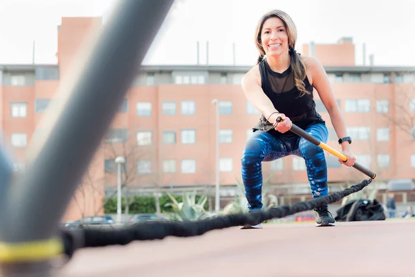 Vista de ángulo bajo de una mujer fitness con una correa de fitness trx en el parque — Foto de Stock