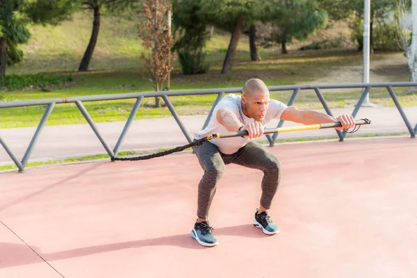 Deportista haciendo ejercicio con una correa de fitness trx en el parque —  Fotos de Stock