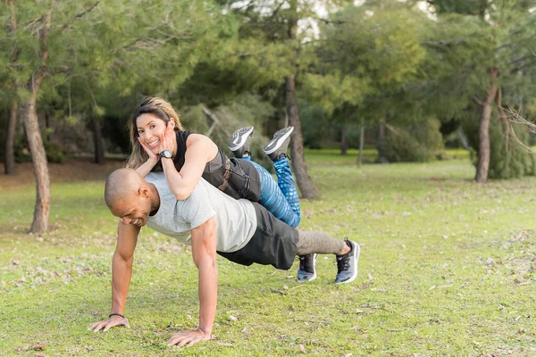 Pareja de fitness haciendo flexiones en el parque. Mujer en la espalda del hombre — Foto de Stock