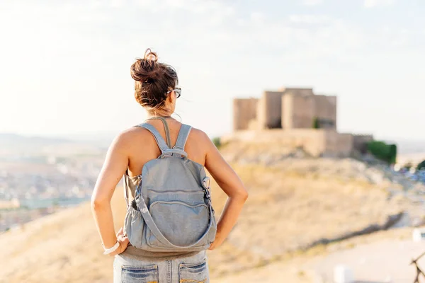 Woman in summer clothes standing and looking at a medieval castle