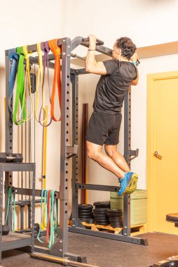 Athlete man doing pull ups exercise with bar in gym