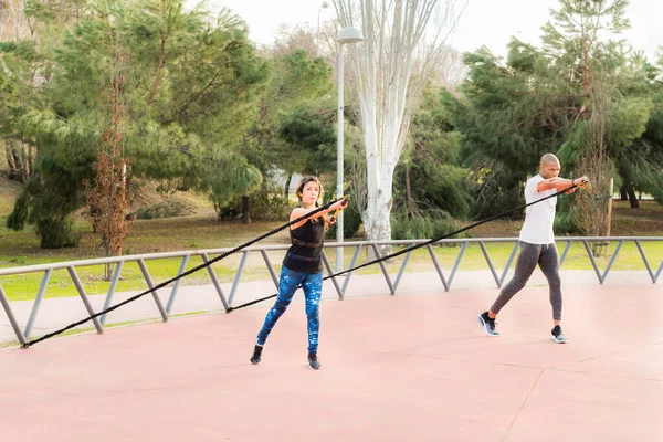 Pareja de fitness haciendo ejercicio con una correa de fitness en el parque —  Fotos de Stock