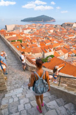Merdivenlerden inen, kırmızı çatıları ve Adriyatik Denizi olan Dubrovnik Eski Kasabası 'na bakan bir kadın.