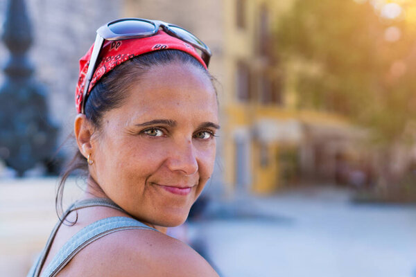 Женщина в красной бандане и солнечных очках улыбается во время летних каникул