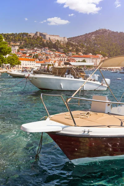 Gemiler, arka planda Hvar kasabası ve tarihi kalesiyle berrak sularda demirledi.
