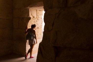 Antik kapı girişinde duran kadın dışarıya bakıyor, çıkış ve merak buluyor.