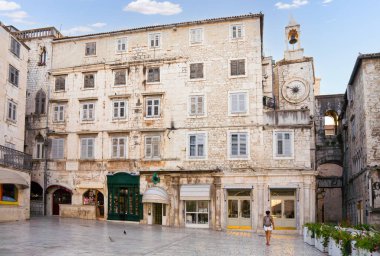 Avrupa şehir meydanında tarihi mimari ve saat kulesinin yanından geçen bir kadın.