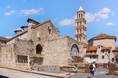Antik Roma harabelerinin ve temiz gökyüzünün altındaki tarihi mimarinin yanından geçen bir adam.