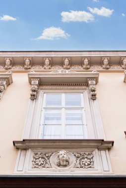 Mavi gökyüzünün altında detaylı oymalarla süslenmiş tarihi bina cephesi.