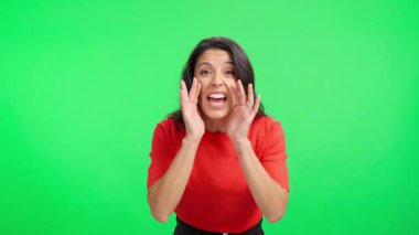 Duygusal olarak el kol hareketi yapan ve yeşil perde arkasında kameraya bağıran bir kadın.