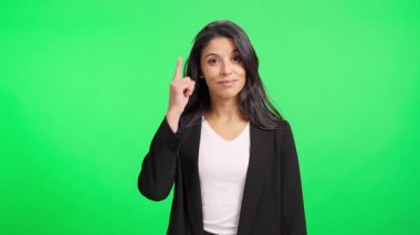Genç iş kadını doğrudan kameraya konuşuyor ve yeşil ekran arka planına işaret ediyor.