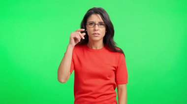 Genç İspanyol kadın gözlüğünü takıyor ve yeşil ekranda şok ve şaşkınlıkla tepki veriyor.